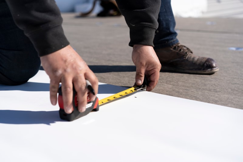 Hands,Of,Roofing,Construction,Worker,Measuring,Tpo,Materials